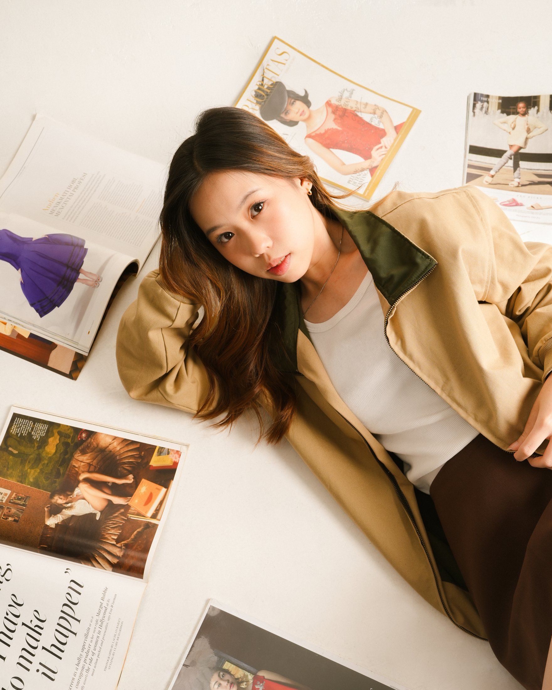Model lying among magazines in the khaki zipper jacket